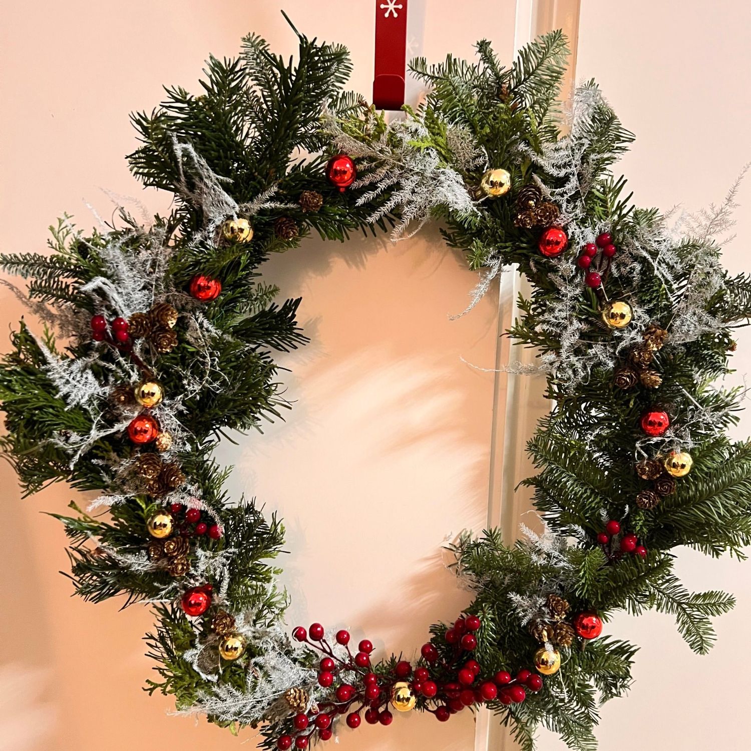 A Christmas wreath of fresh pine, pine cones and red berries hanging on a door